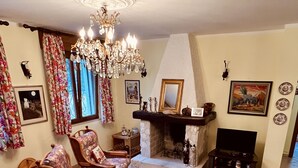 A cozy living room with wicker furniture, a fireplace, and a chandelier. - Villa nestled in the countryside, within walking distance of the sea! (Rodi Garganico, Puglia)