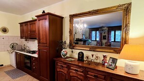 A kitchen with wooden cabinets, a microwave, and a large mirror. - Villa nestled in the countryside, within walking distance of the sea! (Rodi Garganico, Puglia)