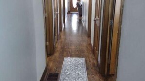 Un pasillo con pisos de madera, un tapete estampado y puertas de madera a ambos lados.