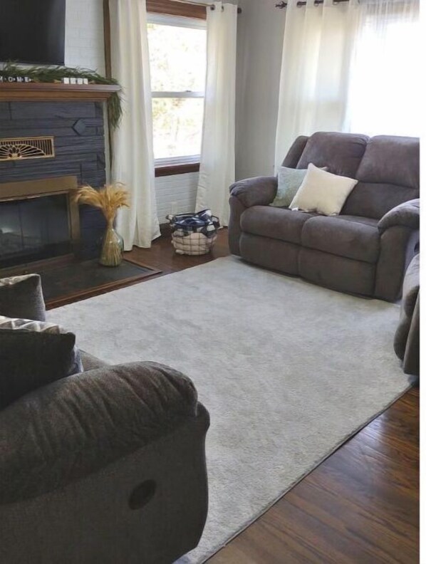 A living room with a fireplace, a sofa, and a rug.