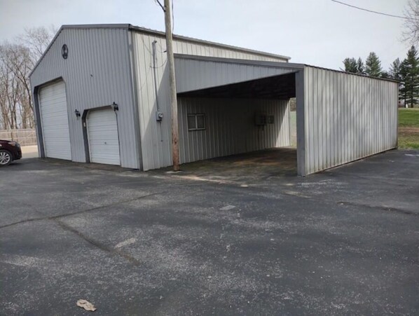 A single-story industrial building with a large garage door and a smaller door, likely used for vehicle storage.