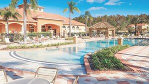 A resort pool with lounge chairs, palm trees, and a gazebo. - Modern 12 BR 11.5 BA, Sleeps 32, 15 mins to Disney (Kissimmee)