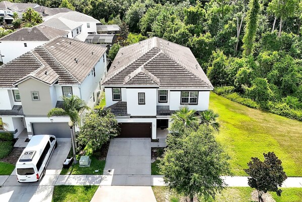 A residential area with houses featuring gabled roofs, a driveway, and a lawn. - Modern 12 BR 11.5 BA, Sleeps 32, 15 mins to Disney (Kissimmee)