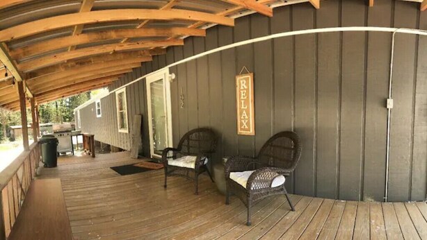 A covered porch with wooden flooring and wicker furniture. - Paradise in the Pines! Your vacation destination! (Hemphill)