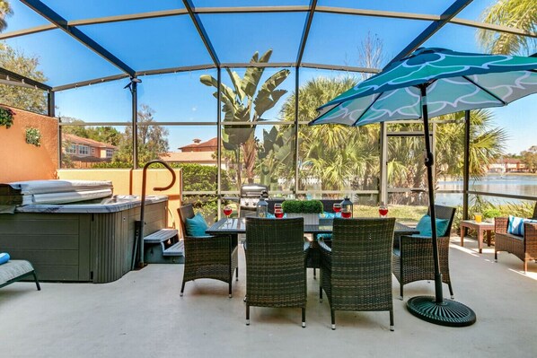 An outdoor patio with wicker furniture, a grill, and a view of a lake.