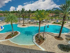 A swimming pool with palm trees and lounge chairs.