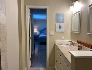 Une salle de bain avec un lavabo, un miroir et une œuvre d’art accrochée au mur.