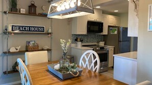 A modern kitchen with white cabinets, a stainless steel refrigerator, and a dining area with a wooden table and chairs. - Destin, FL. Escape to Mirarmar Beach on Seascape resort (Miramar Beach)