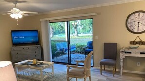 A living room with a television, a coffee table, a chair, a sofa, and a large window with a view of a garden. - Destin, FL. Escape to Mirarmar Beach on Seascape resort (Miramar Beach)