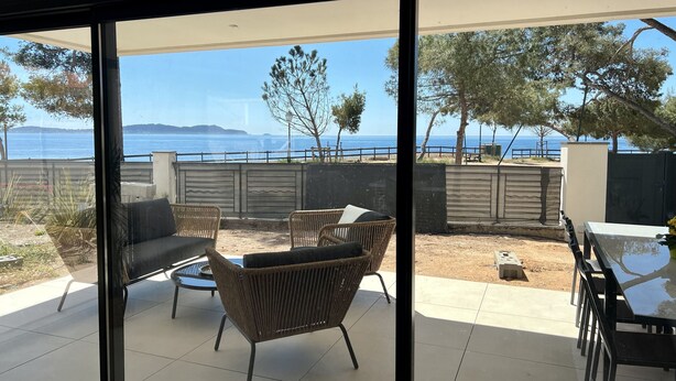 A patio with wicker furniture, a table, and a view of the sea.
