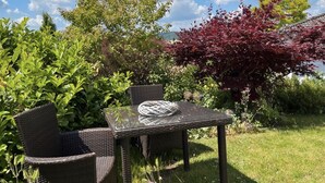 A wicker table and chairs set outdoors with a clear sky and greenery in the background. - Quiet apartment with a great view (Wehretal)