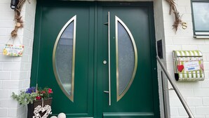 A green double door with a wreath above it, a mailbox, and a basket with flowers. - Quiet apartment with a great view (Wehretal)