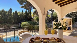 Eine Terrasse mit Pool, Sitzgelegenheiten im Freien und einer Frühstücksecke.