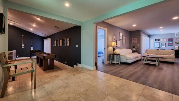 Un amplio salón con mesa de billar, sofá y mesa de centro.
