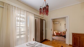 Ein Hotelzimmer mit einem Bett, einem Kleiderschrank, einer Sitzecke mit Sofa und Sesseln sowie einem Kronleuchter.