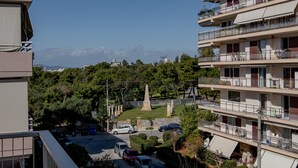 Ein mehrstöckiges Wohngebäude mit Balkonen, einem Parkplatz und einem Denkmal im Hintergrund.