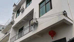 Un immeuble à plusieurs étages doté de balcons, de climatiseurs et d’une lanterne rouge.