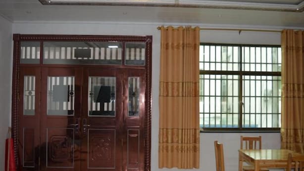 Une pièce avec une porte en bois dotée de panneaux de verre, une fenêtre avec des barreaux et une table avec des chaises.