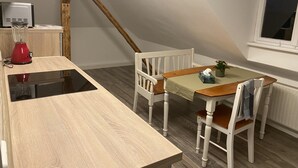 Ein Essbereich mit Tisch, Stühlen, einem roten Mixer und einem Fenster.