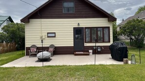 Une maison à deux étages avec un porche à l’avant, une porte coulissante et un espace barbecue couvert.