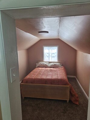 A small, single-bed room with a sloped ceiling and a window with sheer curtains. - Steps from restaurants and the historic Stockman’s Bar and Grill. (Walden)