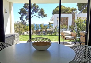 A dining area with a table and chairs, a bowl, and a view of the sea and trees. - T2 with an ocean view in Les Pins Penchés! (Carqueiranne)
