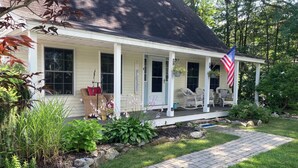 Ein Haus mit Veranda, einer Flagge und einem Garten.