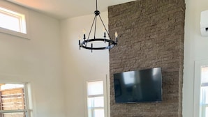 Una sala de estar con chimenea, sofá, una mesa de centro y televisor montado en una pared de ladrillo.