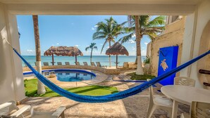 Un espace piscine avec un hamac, des chaises et une vue sur l’océan.