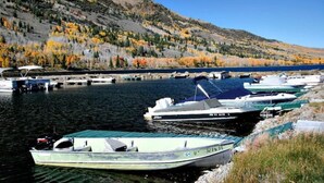 A marina with boats docked along a riverbank, surrounded by autumn-colored trees and hills. - Fishlake family cabin! (Sevier County)