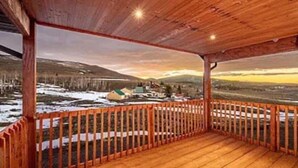 A wooden deck with a view of a snowy landscape and distant buildings. - Fishlake family cabin! (Sevier County)