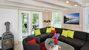 A modern living room with a sectional sofa, a fireplace, and a large window offering a view of the outdoors.
