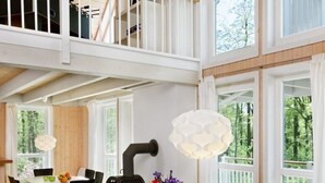 A spacious dining area with a high ceiling, large windows, and a view of the outdoors.