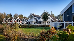 A row of modern houses with white railings and a grassy lawn in the foreground.