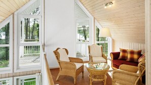 A cozy room with wicker furniture, a glass coffee table, and a red sofa.