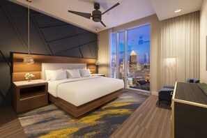 Habitació d'hotel moderna amb un llit gran, un escriptori i vista a la ciutat.