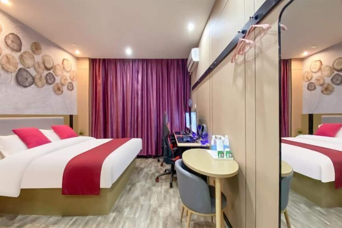 A hotel room with two beds, a desk, and a mirror.