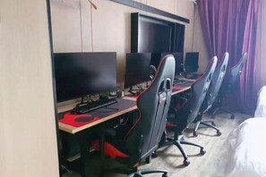 A hotel room with a desk, computer, and a bed.