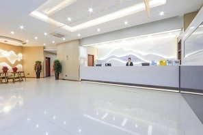 A hotel reception area with a modern design, a reception desk, and a seating area with a plant.