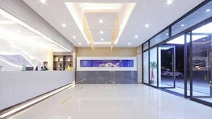 A modern hotel lobby with a reception desk, a large aquarium, and a glass wall providing a view of the outside. - Shankee Hotel (Wujiang Pedestrian Street) (Suzhou)