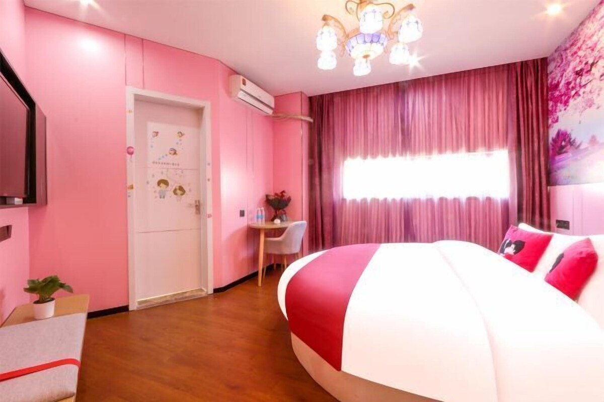 Ett sovrum med rosa tema, med en stor säng, ett skrivbord och en stol.