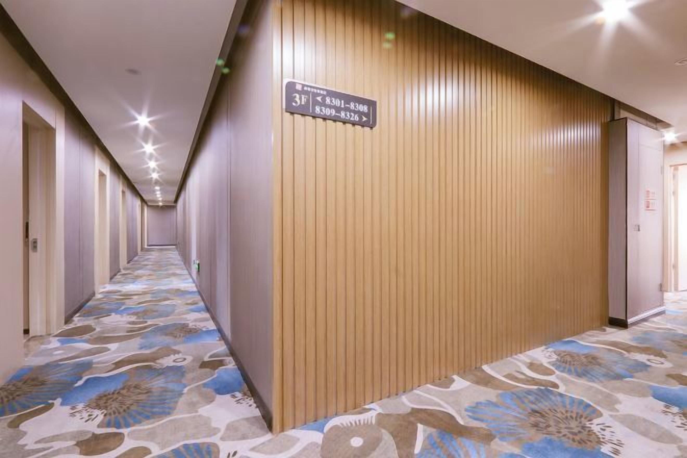 Pasillo de hotel con un letrero que indica la habitación número 31, una pared de madera y una alfombra estampada.