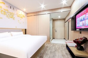 A hotel room with a bed, a TV, a desk with a bouquet of flowers, and a wall with a decorative map. - Shankee Hotel (Wujiang Pedestrian Street) (Suzhou)