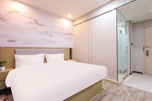 Ett modernt hotellrum med en stor säng, en duschkabin med glasväggar och en vägg av marmor med konstverk.