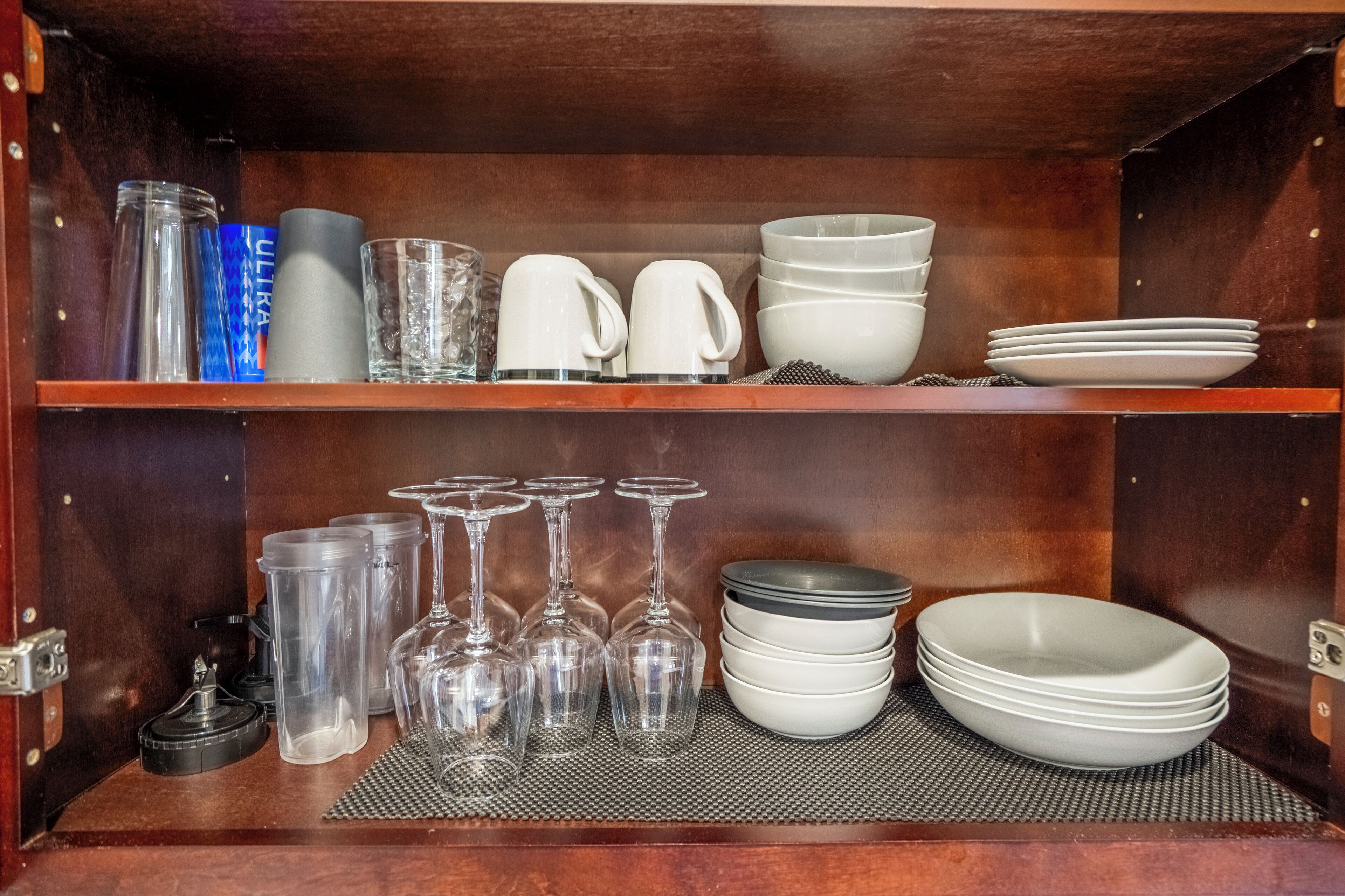 A wooden cabinet with shelves holding various glassware and dishes.