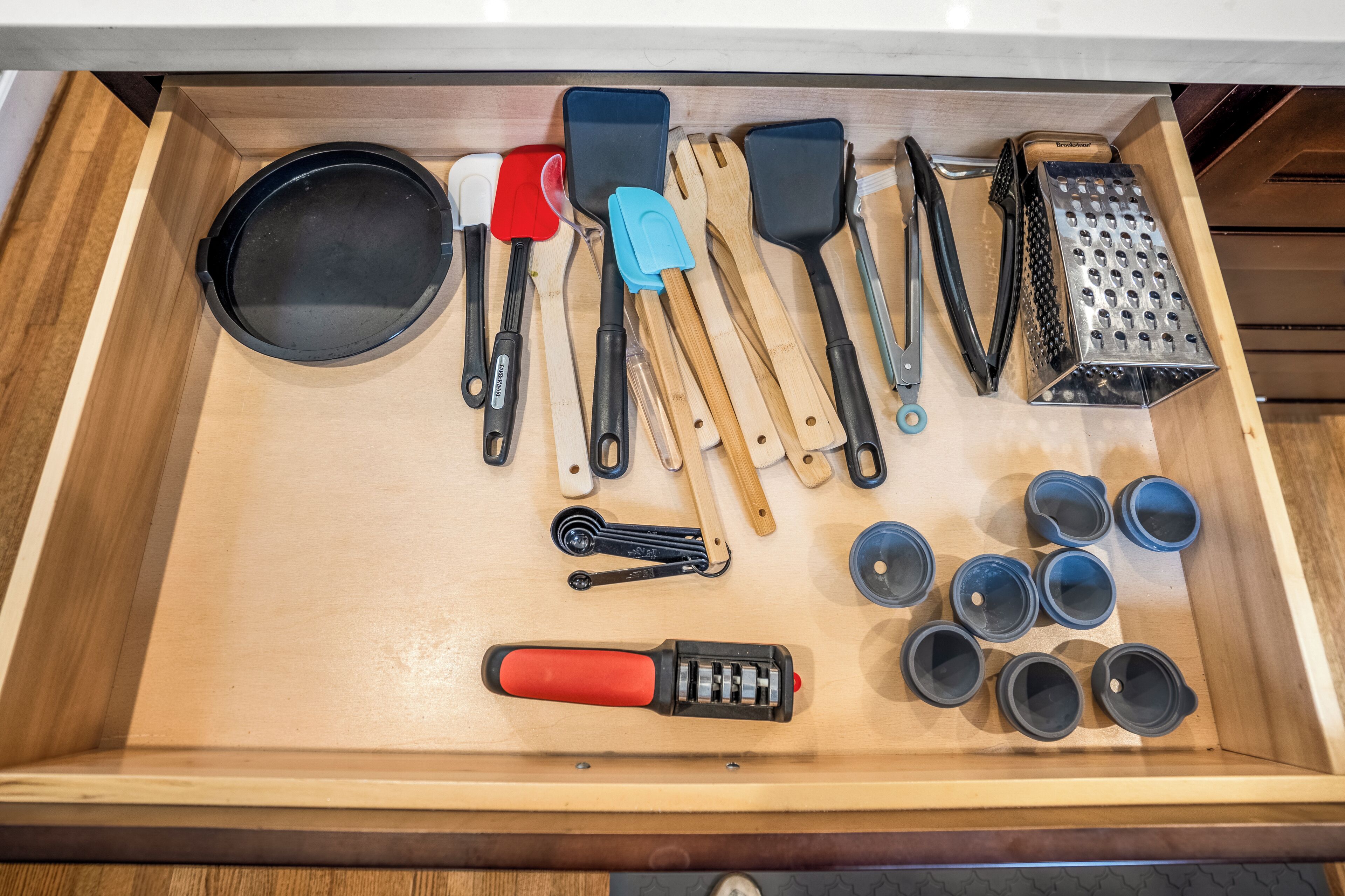 Un cajón con diferentes utensilios y recipientes de cocina.