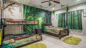 Ein Zimmer mit Etagenbetten, Deckenventilator und einem Wandbild zum Thema Wald.