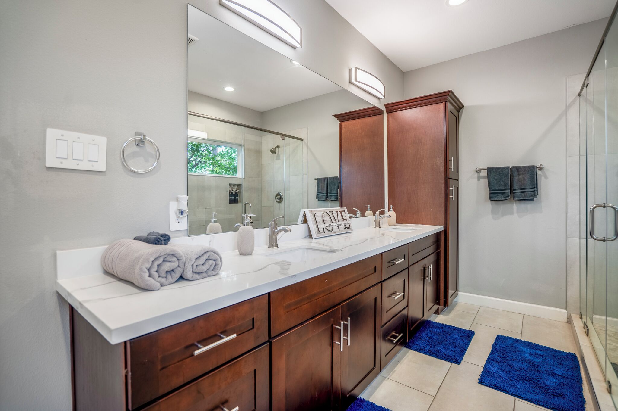 Une salle de bain moderne avec un grand miroir, un meuble-lavabo double et une cabine de douche en verre.
