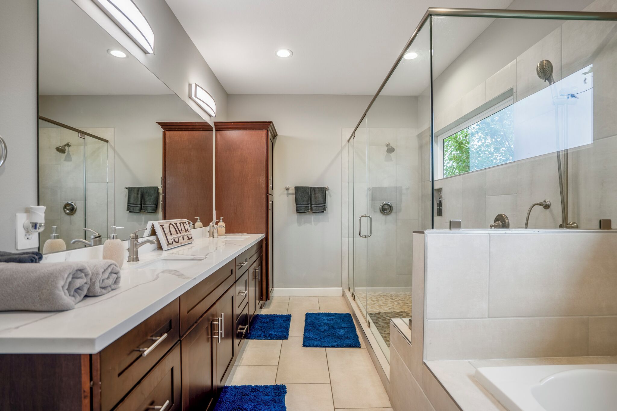 Un baño moderno con ducha de vidrio, un espejo grande y un tocador doble.