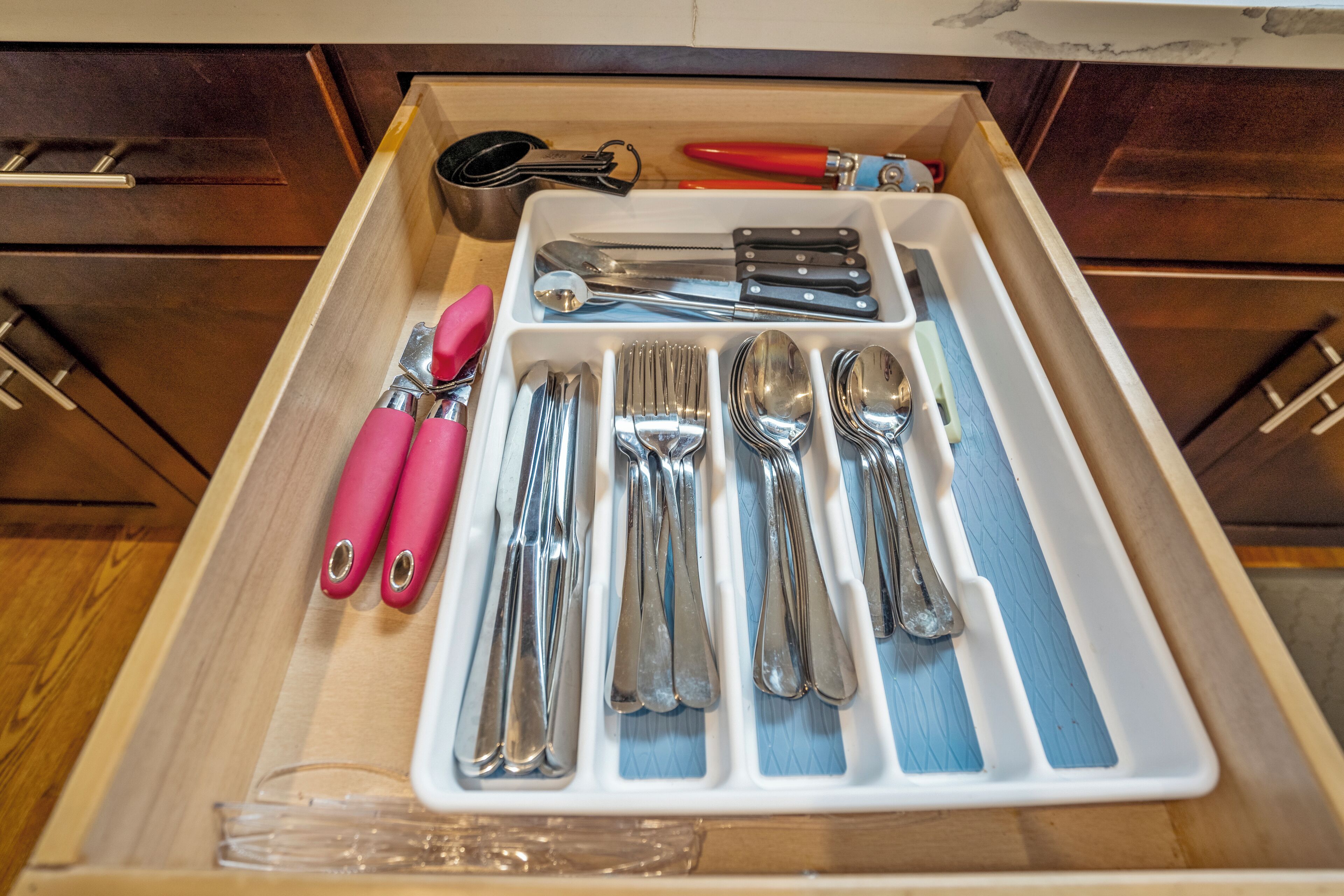 A drawer with neatly organized kitchen utensils including knives, forks, and spoons.